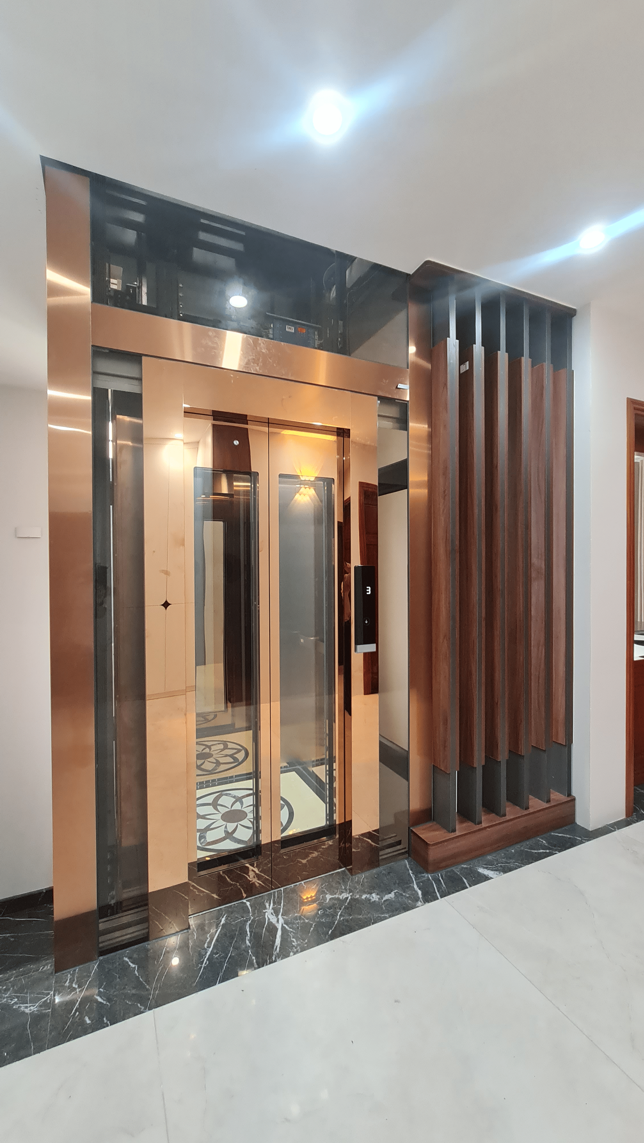 Cửa tầng thang máy inox mạ đồng bên vách lam gỗ, sàn cabin hoa văn, biệt thự Văn Giang - Hưng Yên