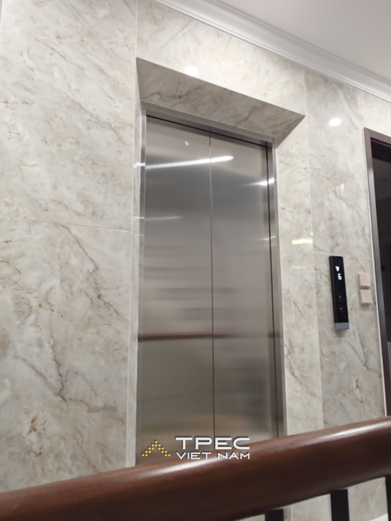 Cửa tầng thang máy inox ốp đá marble cạnh tay vịn gỗ nhà phố Nguyễn Công Hoan