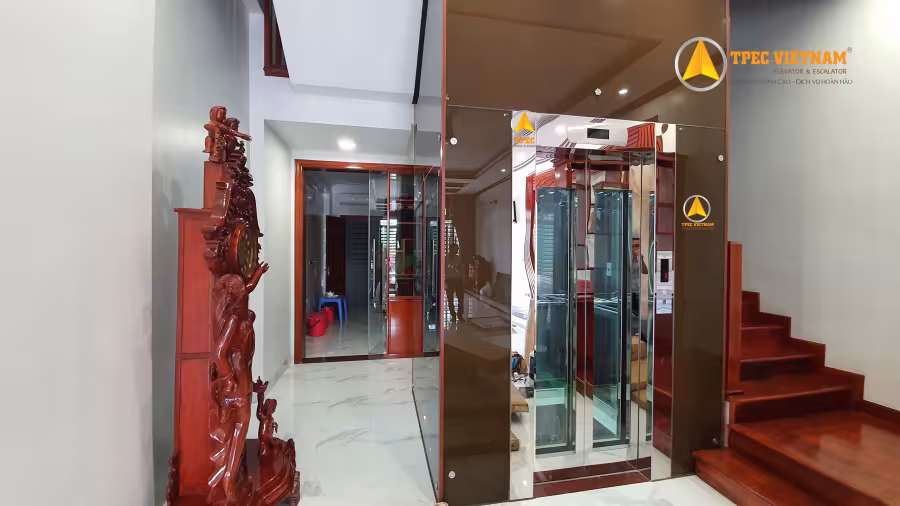 Thang máy gia đình ốp vách kính inox gương lắp cạnh cầu thang trong nhà phố