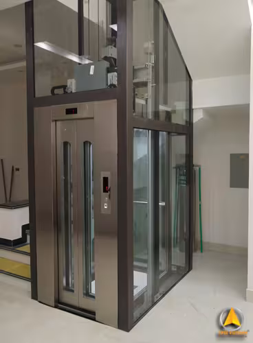 Thang máy gia đình khung thép chấn định hình màu nâu, vách kính bao quanh cabin inox trong nhà