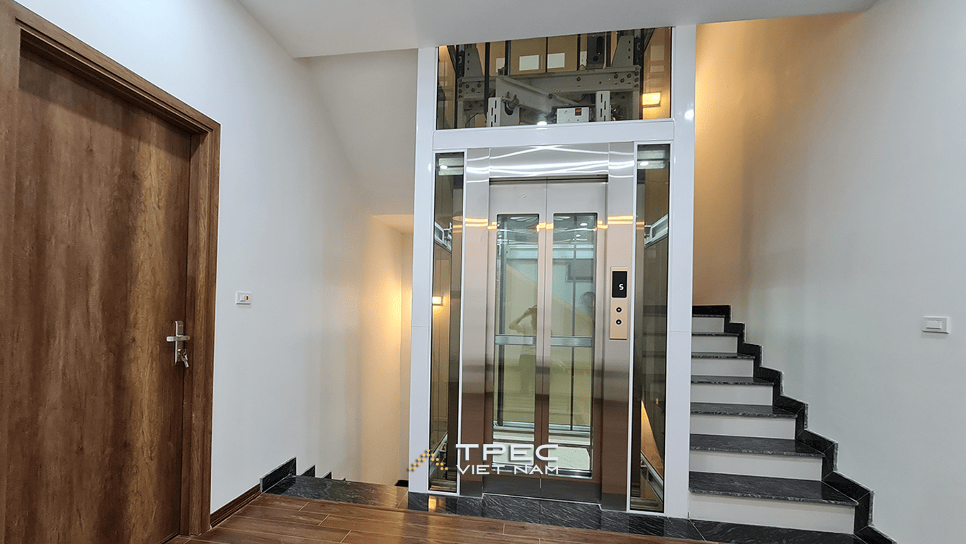 Thang máy kính khung trắng, cửa cabin inox vàng gương tại nhà phố Him Lam Vạn Phúc