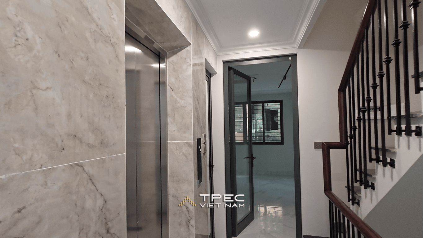 Sảnh thang máy inox ốp đá cạnh cầu thang lan can sắt nhà phố Nguyễn Công Hoan