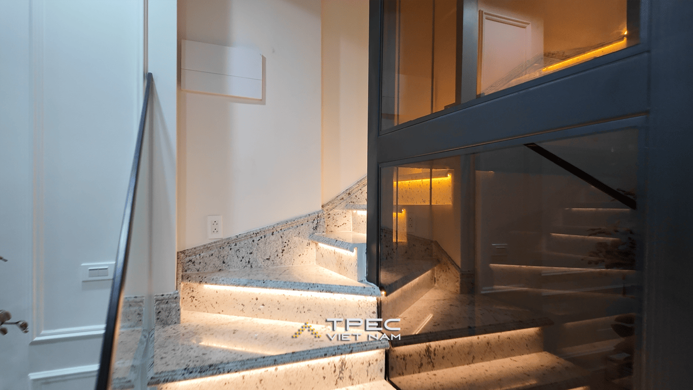 Cầu thang bộ ốp đá lát đèn LED kết hợp thang máy kính đặt giữa nhà phố Trung Kính