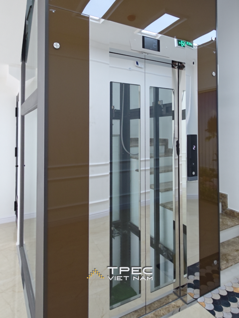 Cửa thang máy kính khung nâu đồng cạnh cầu thang tòa văn phòng tại Mỹ Đình