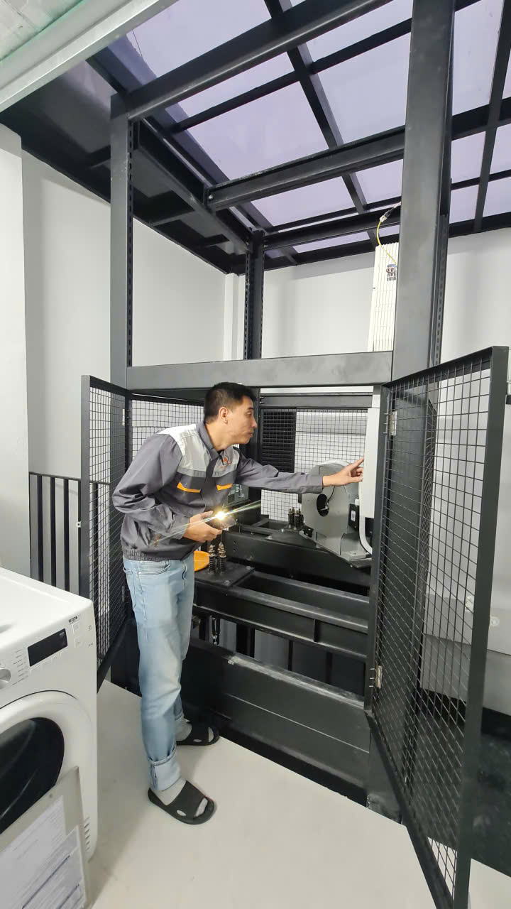 Kỹ thuật viên soi đèn kiểm tra máy kéo trong phòng máy khung thép mái kính tại Hà Đông