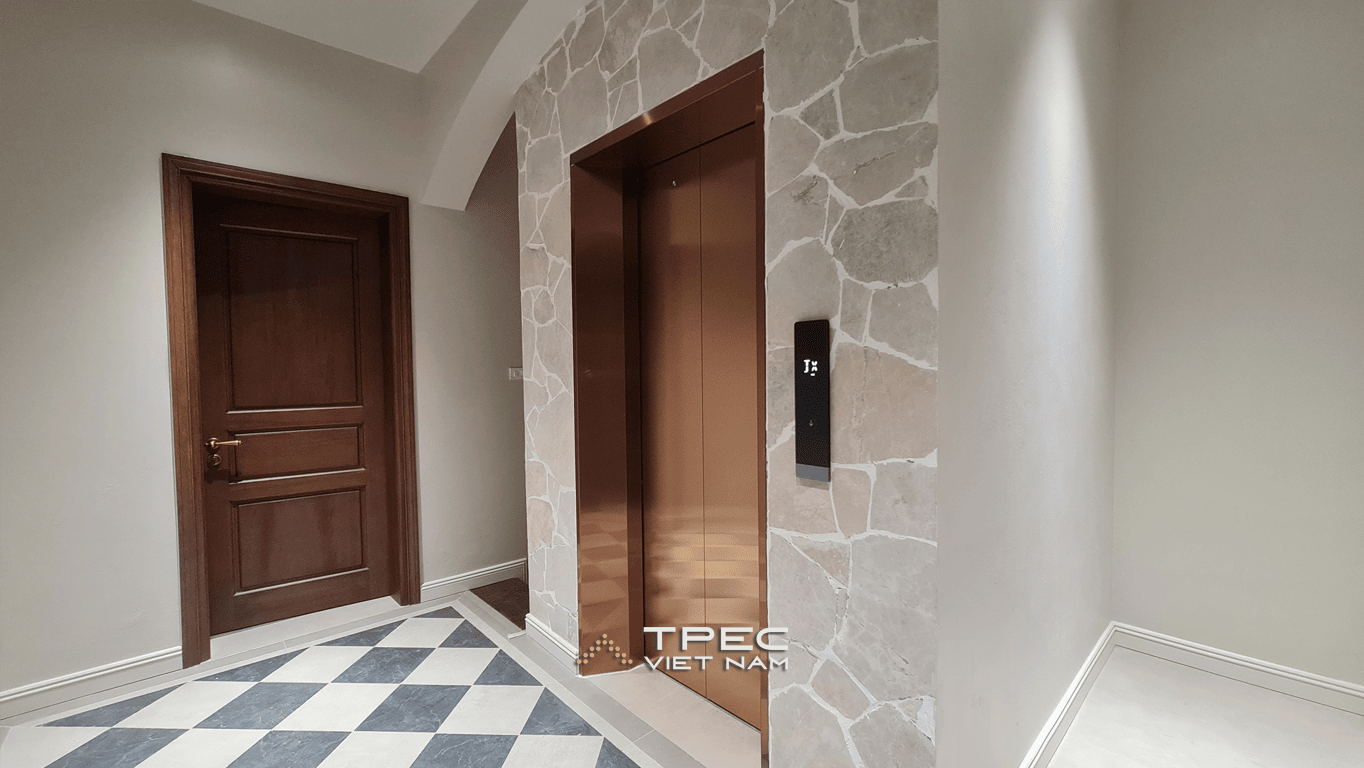 Cửa thang máy inox đồng ốp đá bên sàn lát caro trắng đen tại biệt thự 450kg
