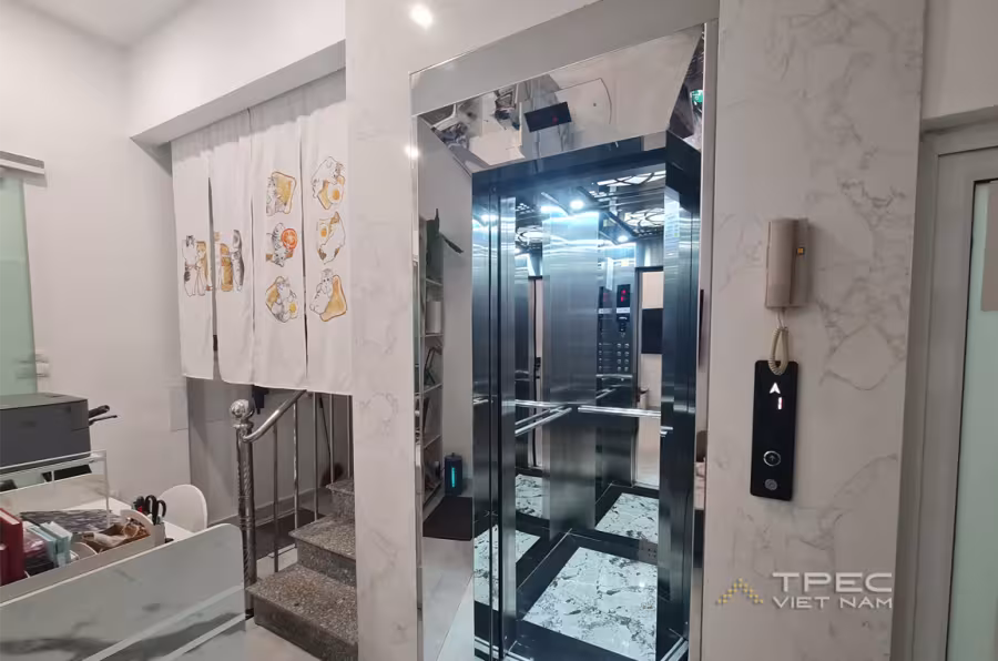 Cabin thang máy gia đình cửa inox gương lắp cạnh cầu thang bộ trong nhà