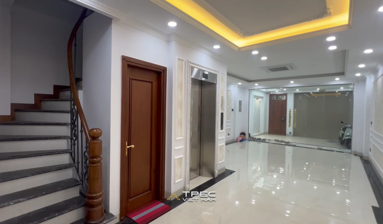 Thang máy gia đình inox cạnh cầu thang bộ trong sảnh nhà phố dự án VOV