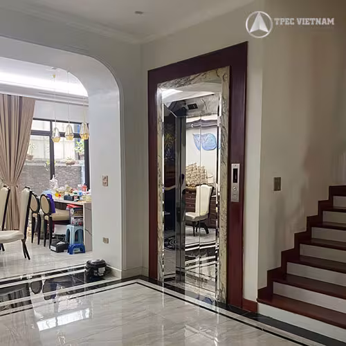 Kỹ thuật viên lau vệ sinh bảo quản thang máy gia đình vách kính bên cạnh cầu thang