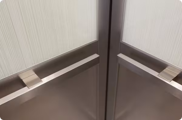 Cận cảnh tay vịn inox lắp trong góc cabin thang máy gia đình vách sọc sáng