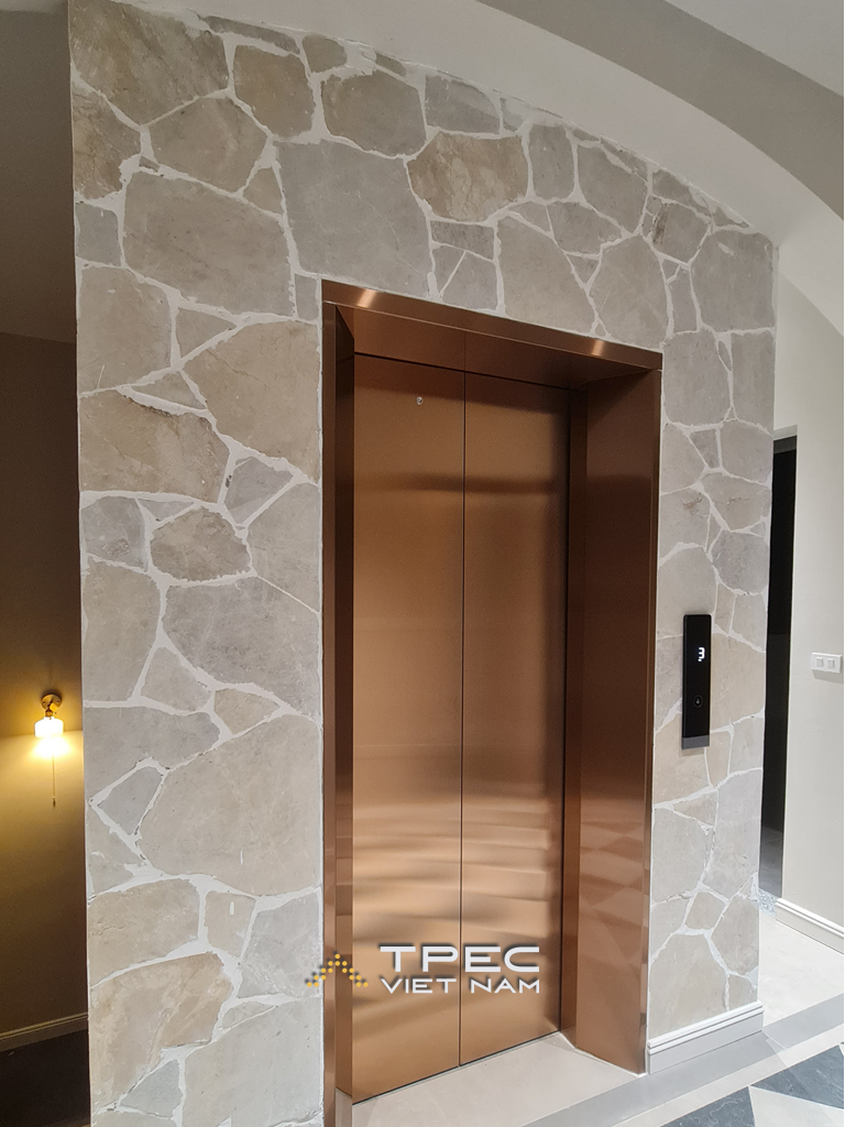 Cửa tầng thang máy inox màu đồng ốp đá tự nhiên tại biệt thự sang trọng