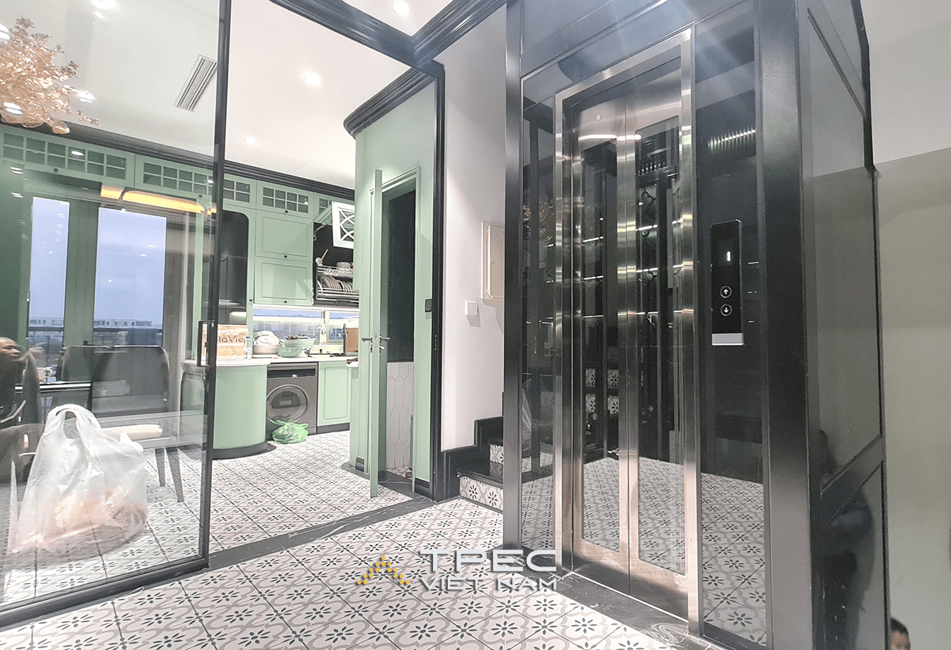 Thang máy kính inox đặt cạnh gian bếp xanh pastel, nhà liền kề The Manor Hà Nội