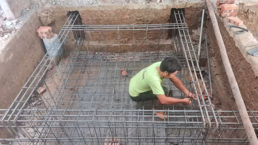 Thợ buộc thép gia cố đáy hố pit thang máy tại công trường, khung cốt thép chịu lực